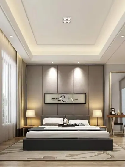 A bright and spacious bedroom with a simple, elegant design. The room features a custom upholstered headboard with accent lighting and an integrated desk area.