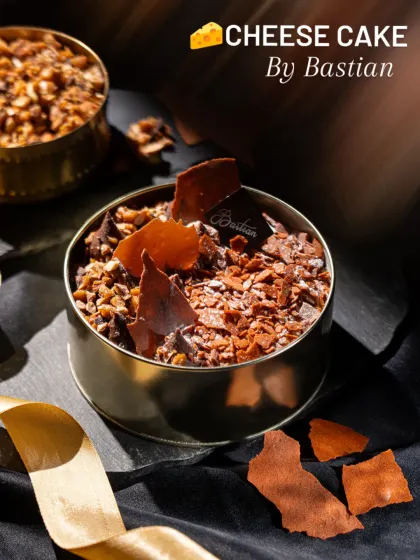 A cheesecake from Bastian with dramatic shards of chocolate. This shot emphasizes texture and composition, presenting the dessert as a modern culinary creation.
