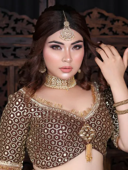 The complete look, featuring a beautiful brown and gold lehenga, complemented by warm-toned makeup and an elegant maang tikka.