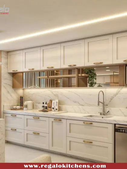 A beautiful kitchen design featuring white shaker-style cabinets, a marble backsplash, and gold hardware. The reflective gold inlay adds a touch of glamour and luxury.