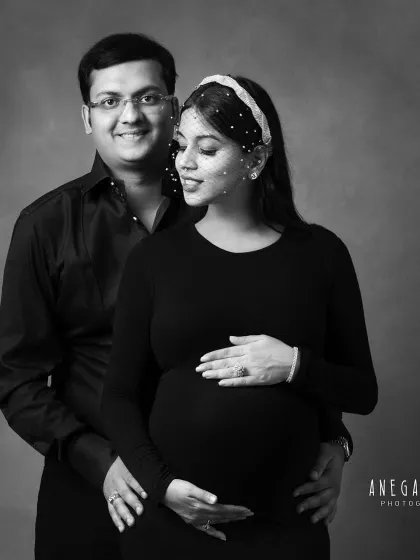 A close-up black and white portrait of an expecting couple. Her serene expression and his proud smile are beautifully captured.