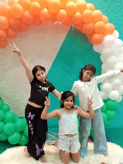 Kids celebrating at a national festival event, posing in front of a large tricolor balloon ring.