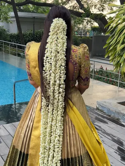A full back view of the viral 'Mogra' hairstyle paired with a pleated lehenga. This look is a guaranteed head-turner and shows my expertise in creating elaborate floral hairstyles.