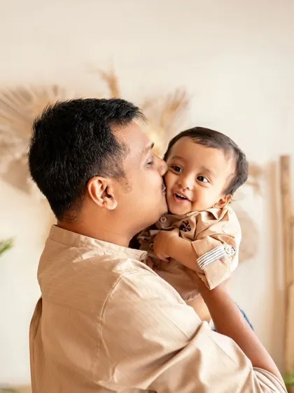 A father gives his son a sweet kiss on the cheek. The boy's happy smile shows how much he loves his dad.