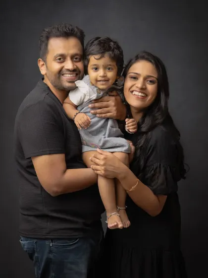 A happy family of three in a classic studio portrait. The coordinated black outfits give this image a sleek and modern feel.