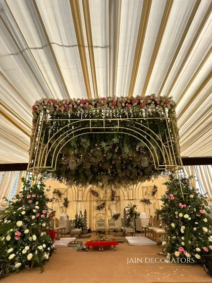 A wide view of the floral canopy mandap, showing how it commands the space. The structure is supported by pillars of flowers, creating a cohesive and immersive garden setting for the wedding.
