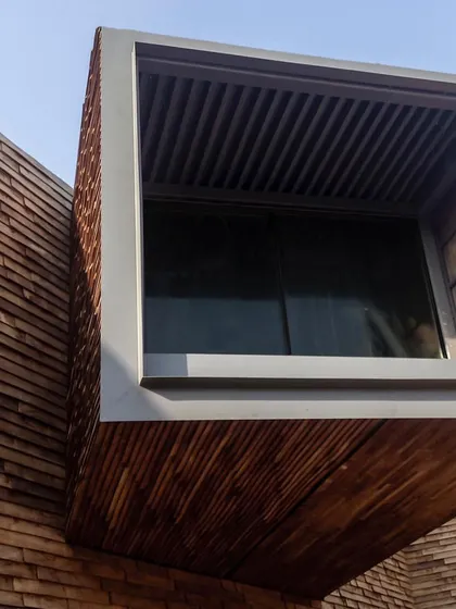 A close-up of the cantilevered window box on the Rhizome House, now clad in wooden shingles. The brise-soleil, or sun screen, is visible inside the frame.