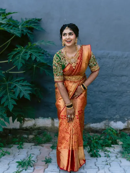 The happiest brides are always the prettiest. This candid shot captures the pure joy of a bride in her beautiful orange and green Kanjivaram saree.