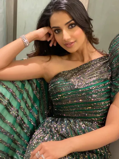 A close-up, seated portrait in the sparkling green gown. This intimate shot captures a moment of quiet confidence amidst the glamour of the event.