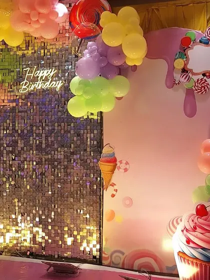 A close-up of the Candyland backdrop details. This shot highlights the "Happy Birthday" neon sign, the dripping candy-themed frame, and the large cupcake cutout.