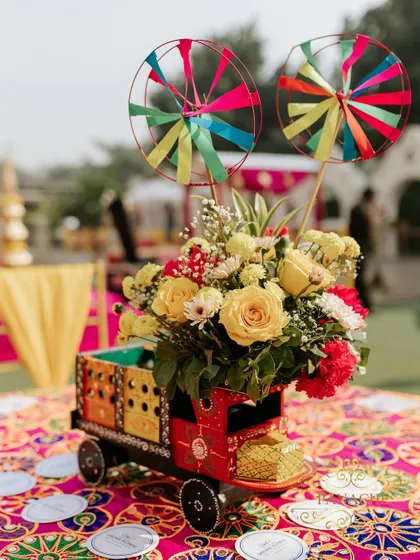Another creative centerpiece designed in a miniature decorative truck, filled with yellow and red flowers. These unique details make the event memorable.