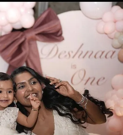 A heartwarming photo of a mother and her one-year-old daughter enjoying the celebration in front of the custom backdrop.