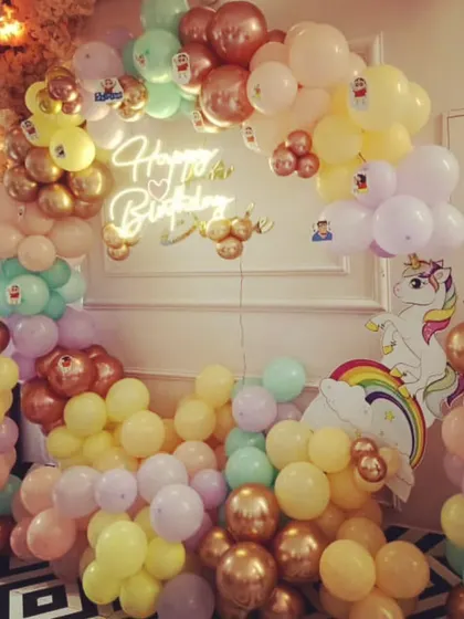 A magical unicorn and pastel rainbow theme for a child's birthday. This full backdrop is filled with balloons in soft colors, a unicorn cutout, and a "Happy Birthday" neon sign to complete the look.