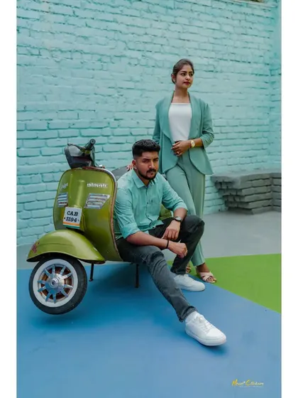 A fun shot featuring a vintage green scooter against a turquoise brick wall. The couple's modern style and the retro prop create a unique and playful vibe.