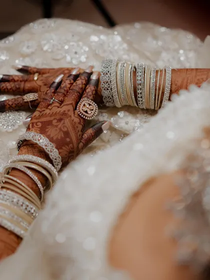 A close-up of the beautiful henna stain, adorned with sparkling bangles and rings. The dark color signifies deep love.