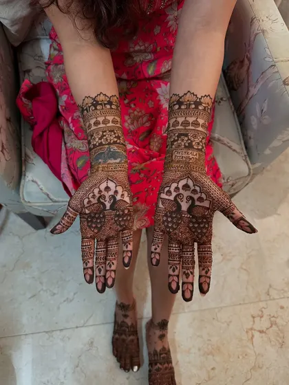 A beautiful display of full bridal henna, with peacocks on the palms and matching intricate patterns on the feet. The design is dense and detailed, perfect for a traditional bride.