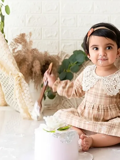 A playful moment captured as she digs into the cake with a wooden spoon during her first birthday session.