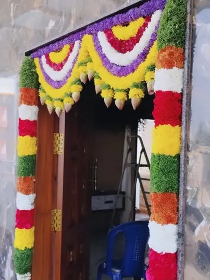 A beautiful entrance door decoration with multi-colored flower garlands and hanging lotus buds.