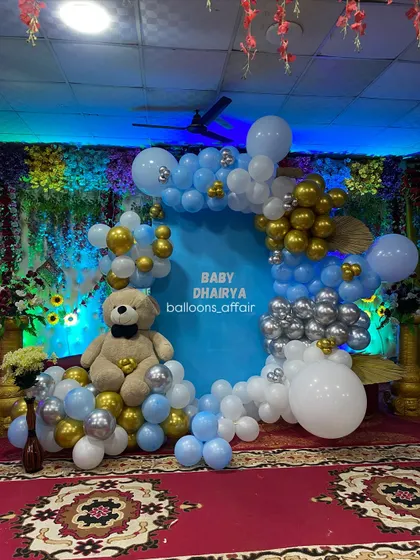 A detailed shot of the teddy bear themed stage decoration. The blue, white, silver, and gold balloons perfectly complement the central blue backdrop for 'Baby Dhairya'.