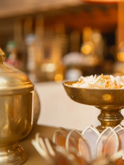 A soft-focus shot of a brass vessel filled with delicate flower petals, ready for a ceremony. The warm glow of the metal and the gentle texture of the petals create a serene and sacred atmosphere, perfect for traditional rituals.