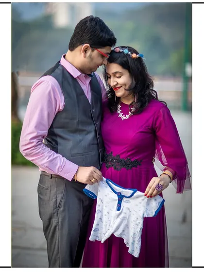 The couple holds up a tiny baby onesie, a sweet prop that adds to the excitement of the shoot.