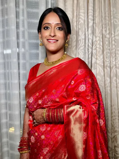 A classic reception look. The rich red of her silk saree is paired with clean, defined eyes and a warm, natural skin finish.