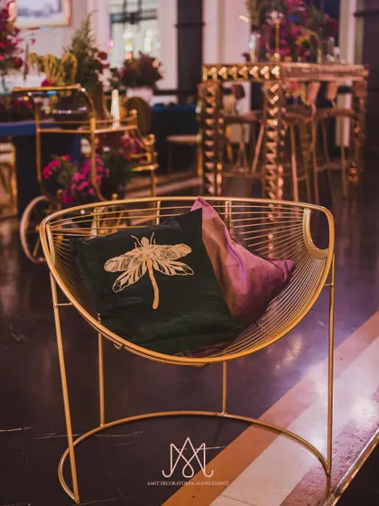 A modern gold wireframe chair accented with custom-embroidered dragonfly cushions, blending comfort with high design.