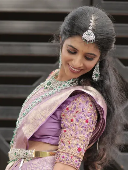 This bride is glowing in a diamond-look alike AD jewellery set. The layered necklaces, maang tikka, and hip belt were all styled to create a coordinated and sparkling look for her reception.