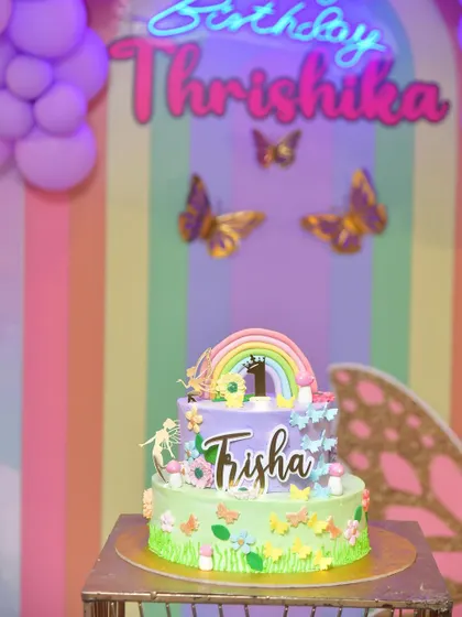A custom cake designed for a butterfly-themed party, featuring a rainbow and delicate sugar butterflies.