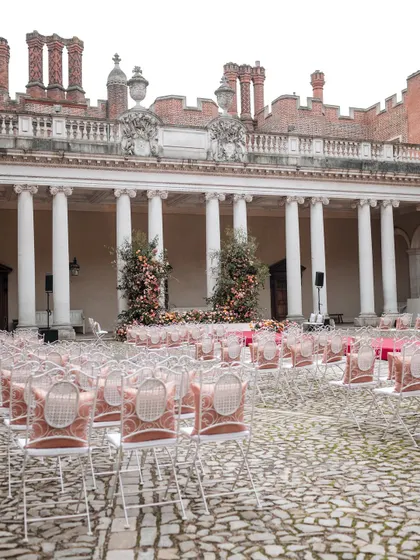The full view of the ceremony space at Hampton Court Palace. The elegant seating and floral mandap create a picture-perfect scene, reminiscent of a classic film.