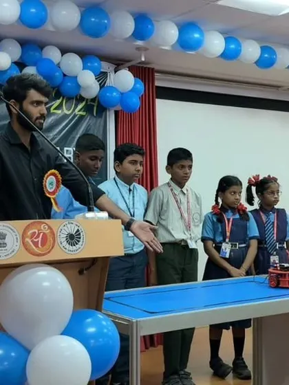An instructor addresses a group of students at the Innovation Fair, explaining the principles behind the robotic models on display.