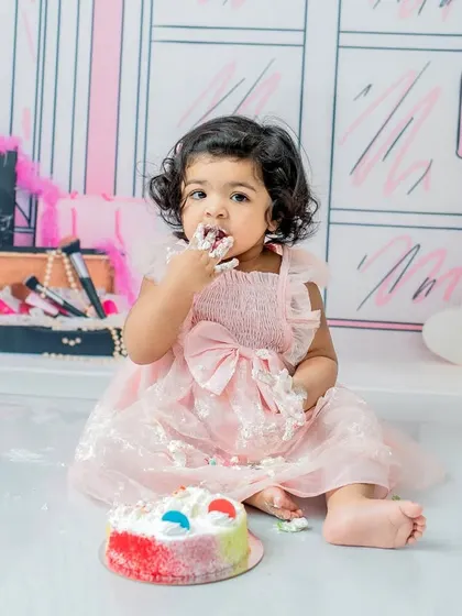 A stylish cake smash with a Barbie theme. This little girl is having her first taste of cake, a sweet moment captured against the chic illustrated backdrop.