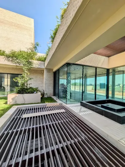 The courtyard of our Dubai Hills villa, showing the interplay of light and shadow created by the overhead trellis. The design includes a water feature that reflects the sky and cools the surrounding space.