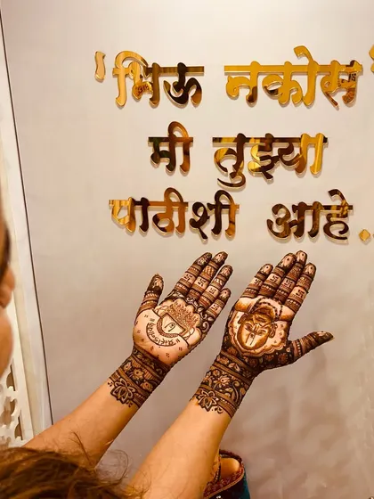 A client displaying her devotional mehendi in front of a spiritual quote. This design features a portrait of Swami Samarth.