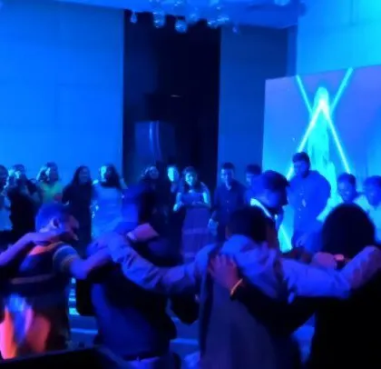 Employees in a huddle on the dance floor, a sign of a great team-building event.