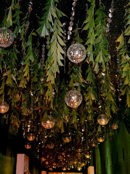 Creating a starry night effect for a sangeet entrance. We hung lush greenery and sparkling disco balls from the ceiling to make guests feel like they were walking under the stars.