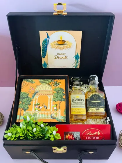 For the whiskey lover, this hamper includes two different miniature whiskeys, Lindt chocolates, and a beautiful notebook, all packed in our black suitcase box.
