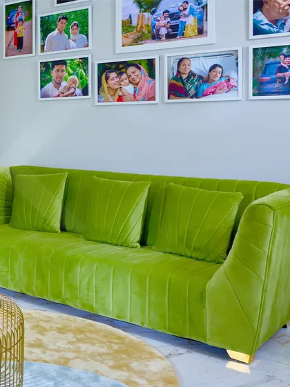 A cozy and elegant family living area with a vibrant green velvet sofa and a gallery wall of family photos.