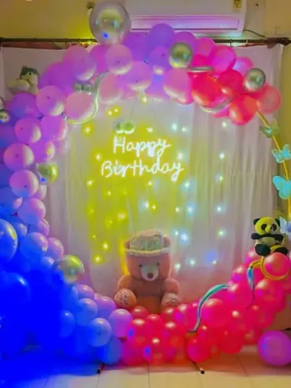 A whimsical and colorful birthday ring setup, perfect for a sweet sixteen or a young-at-heart celebration. The multi-colored pastel balloons, fairy lights, and a central teddy bear create a soft and dreamy party backdrop.