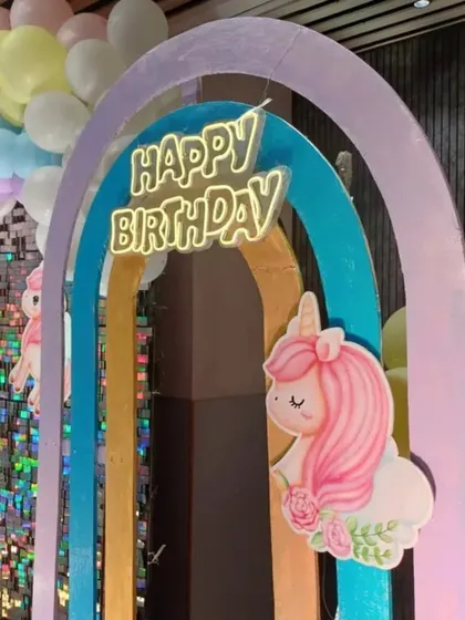 A close-up of the unicorn theme, highlighting the custom-cut unicorn figure, neon "Happy Birthday" sign, and pastel rainbow arch.