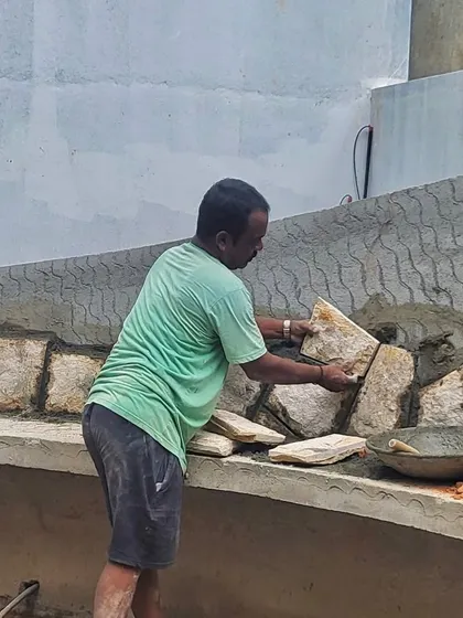 A skilled mason carefully setting stones for an exterior wall. We work closely with our craftspeople, valuing their expertise and ensuring the highest quality of workmanship in every material.