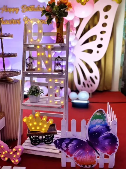 A decorative ladder shelf with light-up 'ONE' letter's and other butterfly-themed prop's.