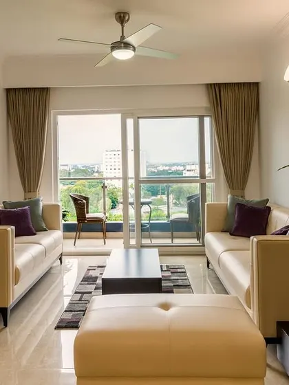 A minimalist living room setup with clean-lined leather sofas, a geometric rug, and a large sliding door leading to a balcony, creating a bright and airy space with a beautiful city view.