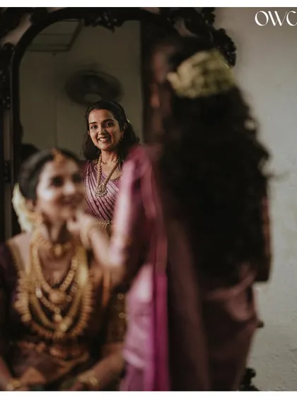 A creative shot using a mirror to capture the reflection of the bride's friend watching her get ready.
