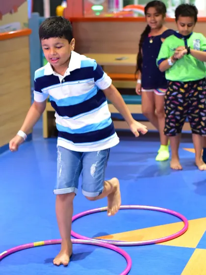 A boy focuses as he hops through a floor obstacle course. My camp activities are structured to challenge kids in a positive way, building both physical skills and concentration.