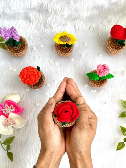 Holding a tiny potted rose, showing how these little creations fit perfectly in the palm of your hand.