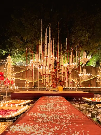 The final, breathtaking view of the floating mandap at Alila Fort Bishangarh. The red aisle, candlelit boats, and dramatic chandelier installation create a scene of unparalleled grandeur.