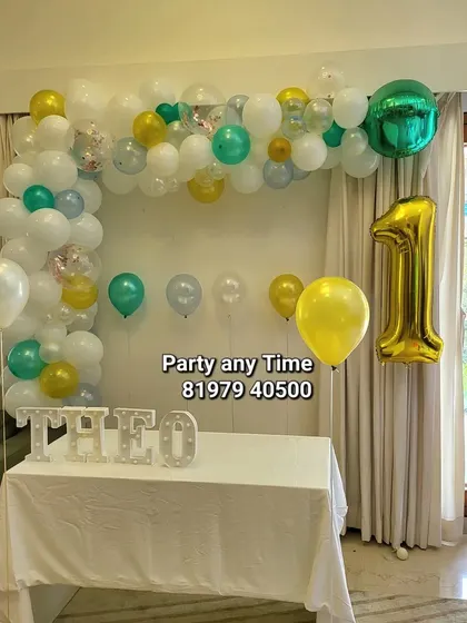 A simple and charming first birthday decoration for a home celebration, featuring a small balloon arch and light-up letters.