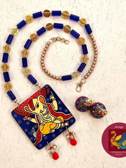 A full view of the Ganesha necklace set, showing how the blue glass beads and brass embellishments complement the hand-painted pendant and jhumkas.