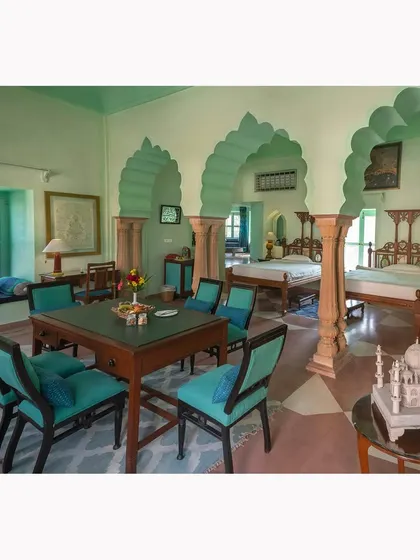 A view of a large, airy suite with distinct living and sleeping areas. The arched architecture and cool color palette are the focus of this interior shot.